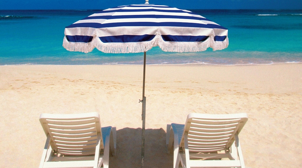 One black and white umbrella and white lounge chairs on Shoal Bay Beach on Anguilla, Caribbean