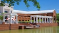 Een gebouw van baksteen met witte kolommen en een overdekte galerij, gelegen aan een waterpartij.