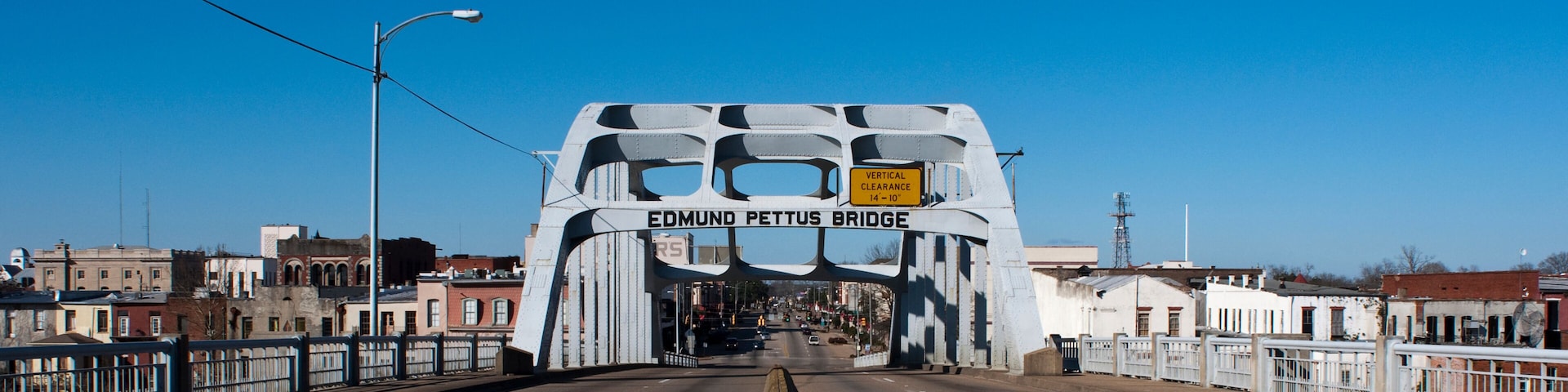 A bridge with the sign 'EDMUND PETTUS BRIDGE' and a vertical clearance sign.