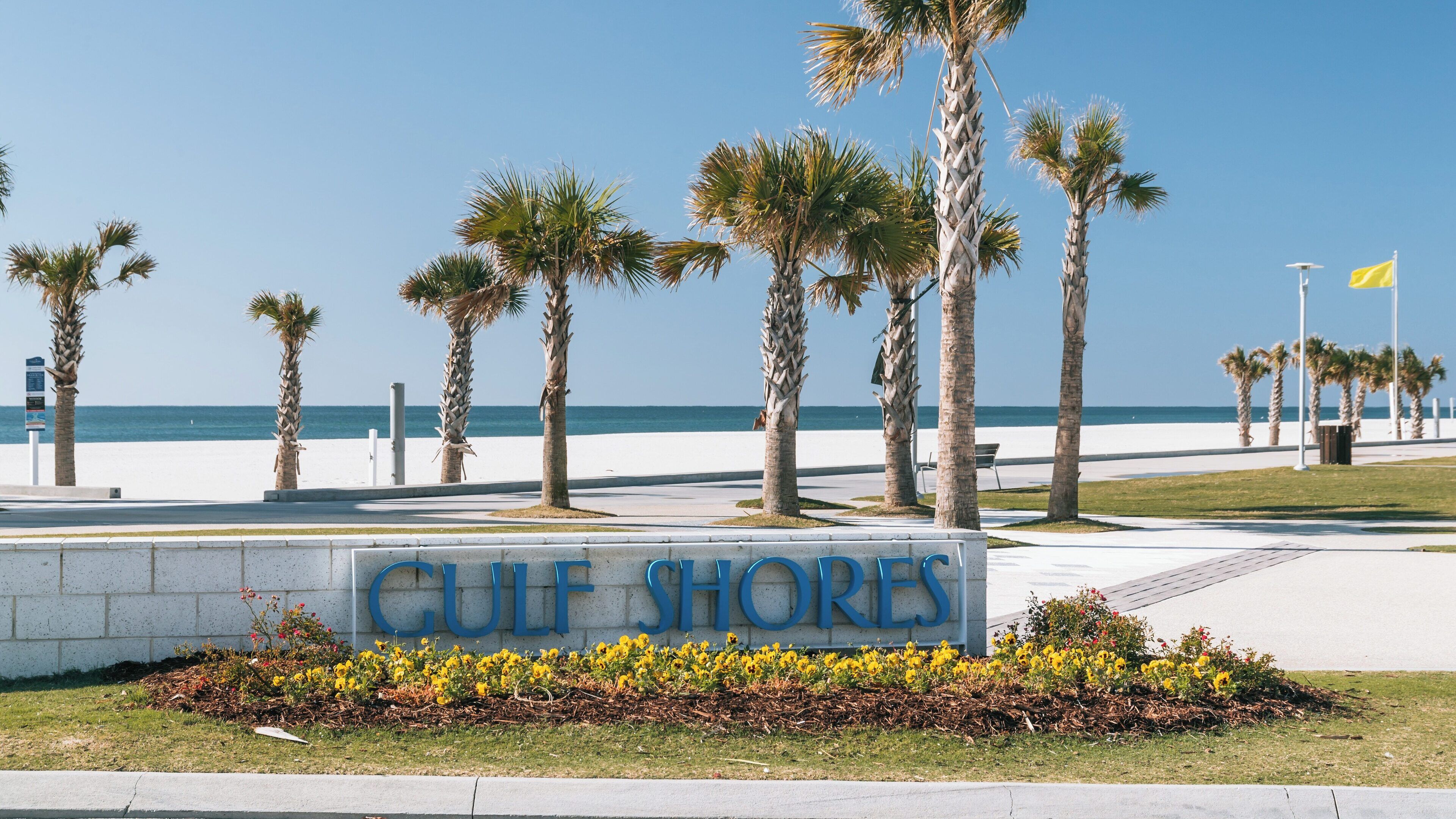 Relaxing day at Gulf Shores Beach in Alabama with clear skies and welcoming palm trees inviting visitors to enjoy the coastal atmosphere