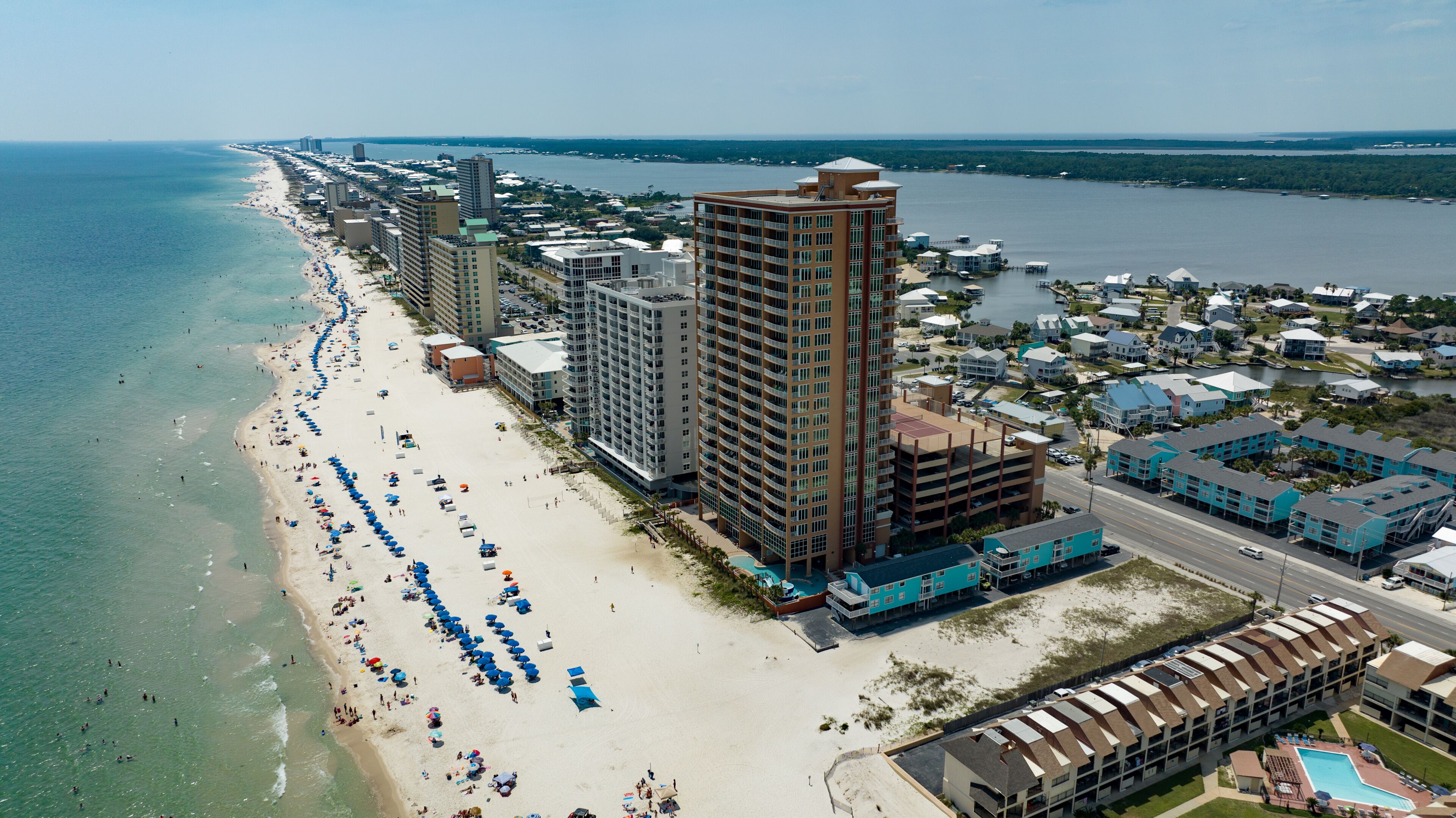 A coastal cityscape with a long sandy beach, high-rise buildings, and a marina.