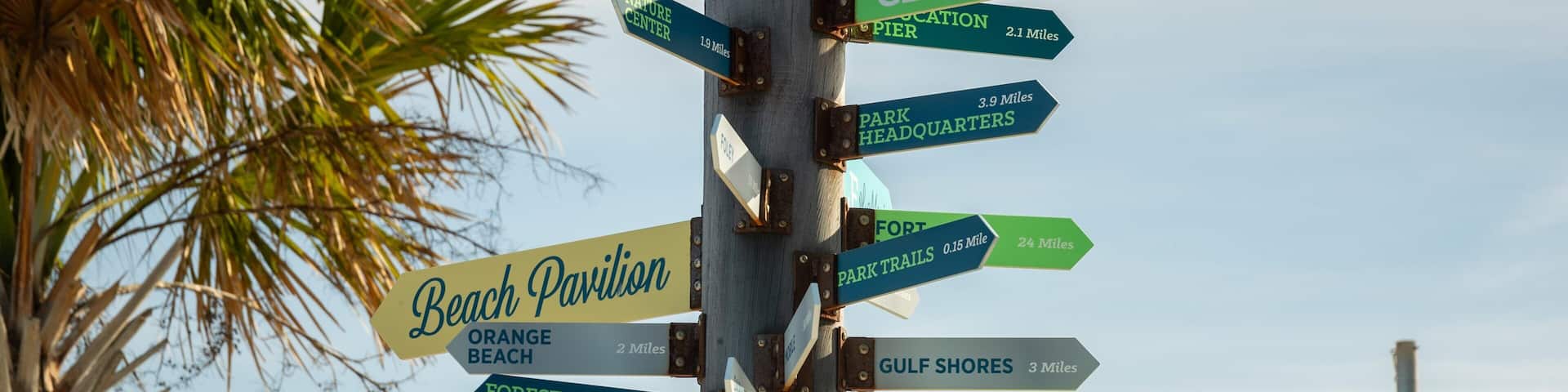 A directional signpost with multiple signs pointing to various destinations such as Beach Pavilion, Orange Beach, Forest Pavilion, and others.