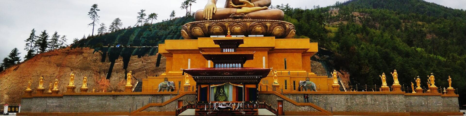 A large seated Buddha statue in front of a temple complex.