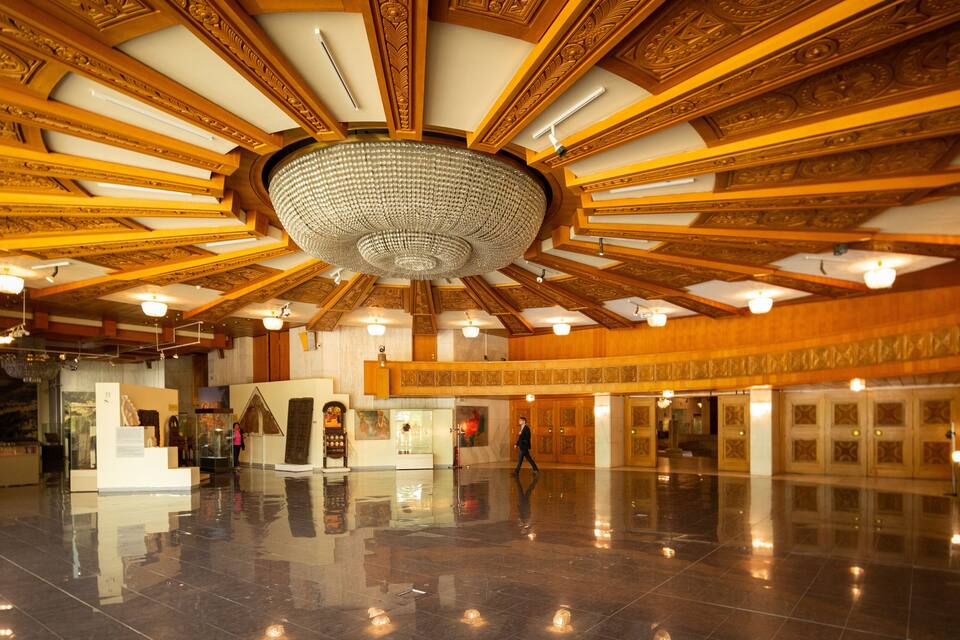 Un salón espacioso con techos de madera decorada y un gran candelabro de cristal.