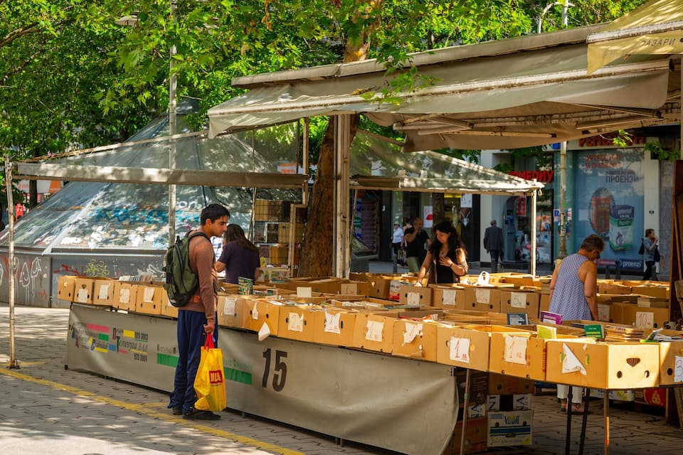 A street market stall with cardboard boxes labeled with numbers and prices.