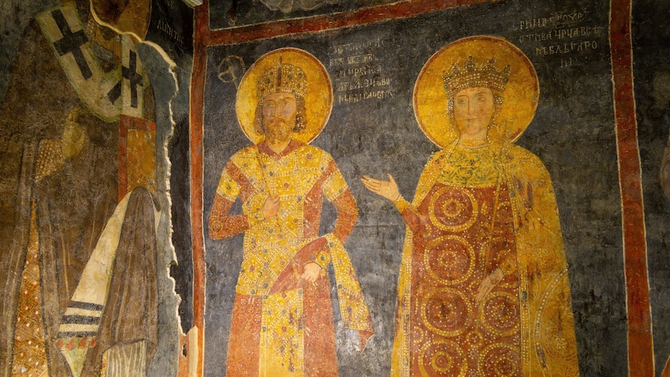 Une mosaïque représentant deux personnages vêtus de robes somptueuses, dont l’un tient un livre.