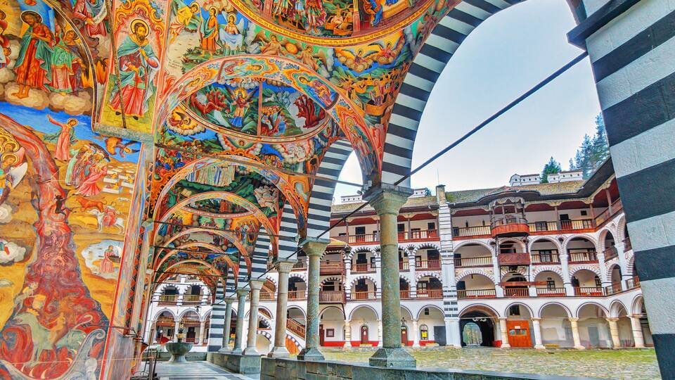 A historic building with ornate frescoes and a series of arches.