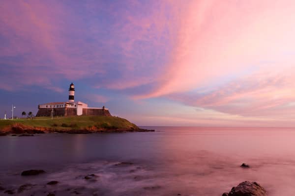 Farol da Barra Beach featuring a lighthouse, a sunset and general coastal views