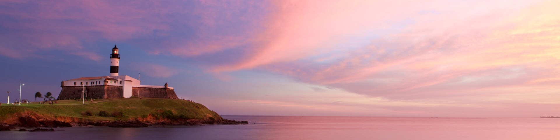 Farol da Barra Beach featuring a lighthouse, a sunset and general coastal views
