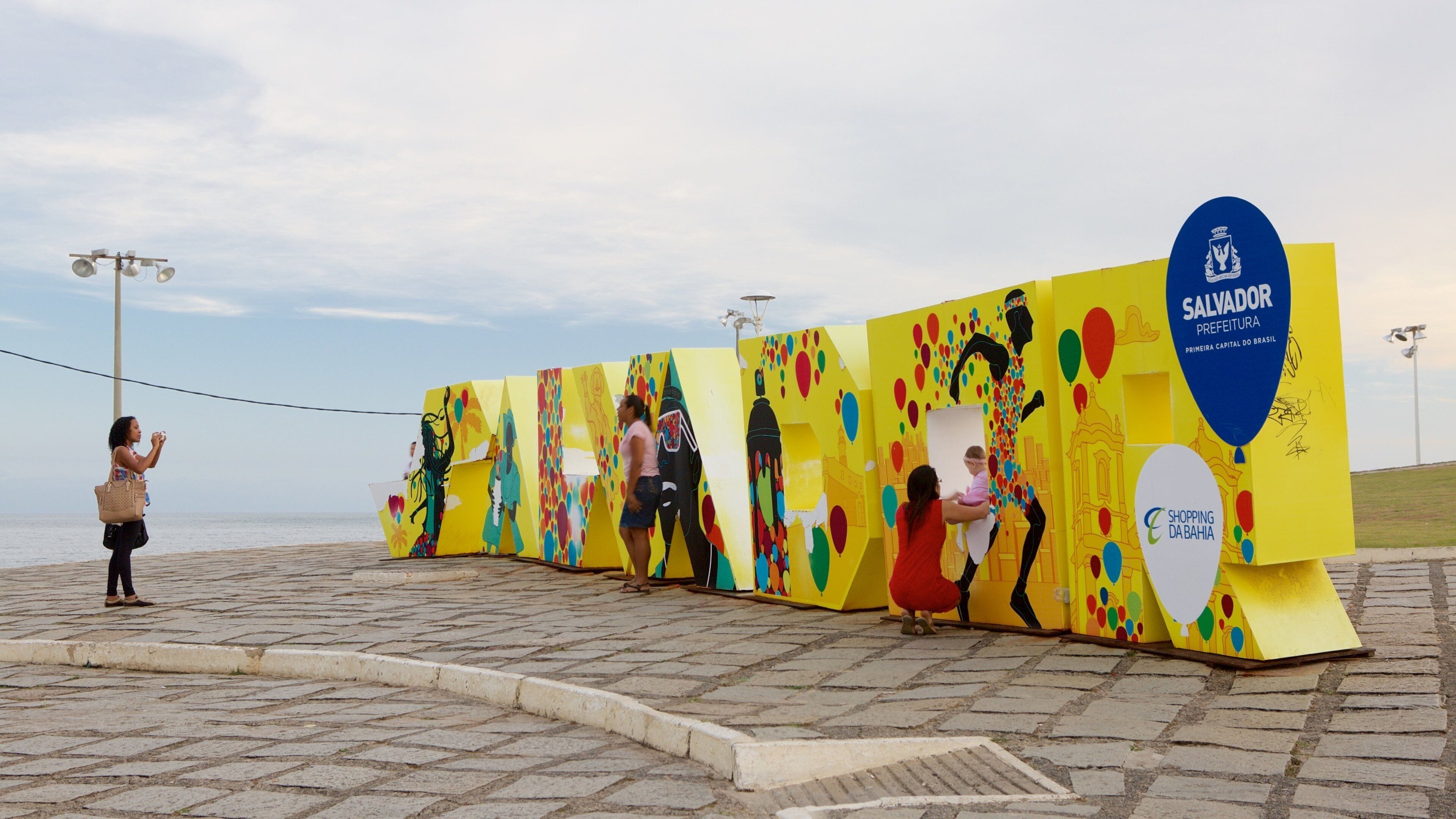 Farol da Barra Beach showing outdoor art as well as a small group of people