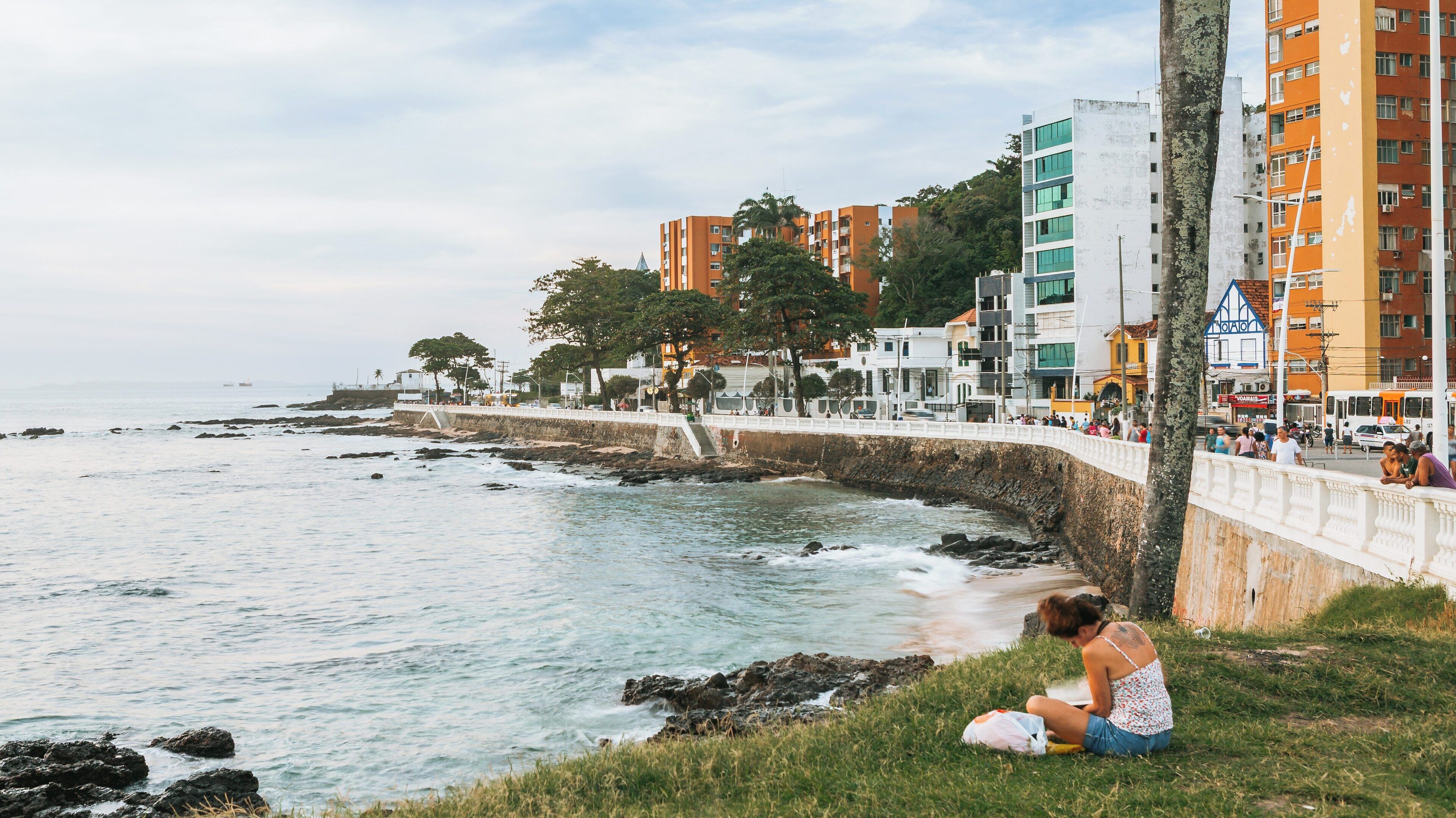 Coastal view of Farol da Barra Beach bustling with visitors and beachgoers in Salvador, Bahia on a serene day with gentle waves