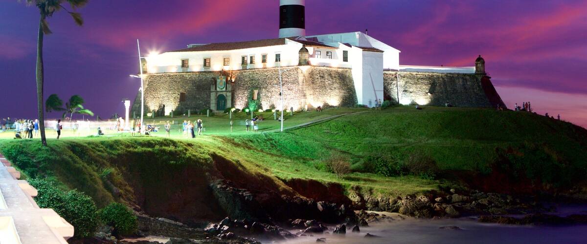 Playa Farol da Barra que incluye un faro, escenas nocturnas y vistas de una costa
