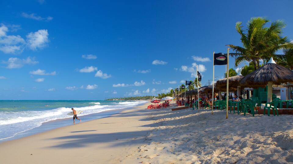 A beach with palm trees, thatched umbrellas, and a clear blue sky.