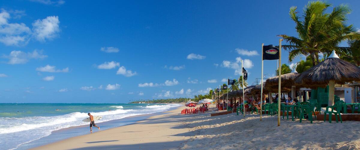 A beach with palm trees, thatched umbrellas, and a clear blue sky.