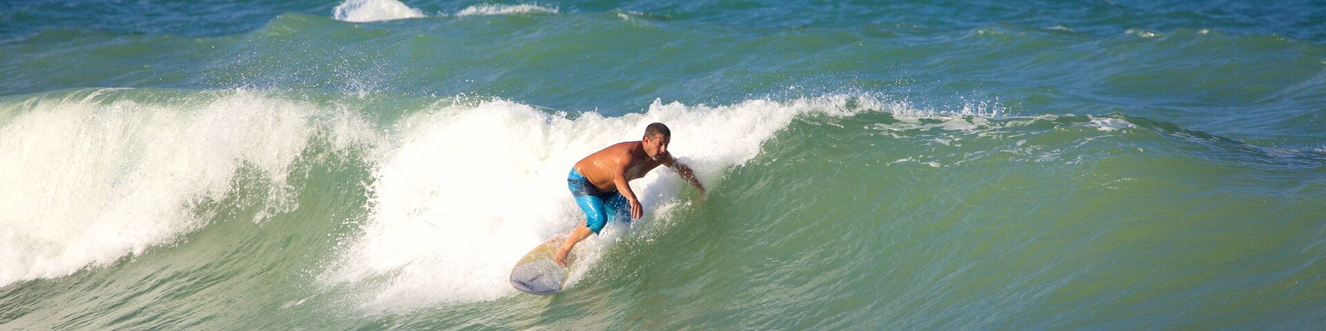 Ein Surfer reitet eine Welle im Meer, während sich eine andere Person in der Nähe befindet und schwimmt.