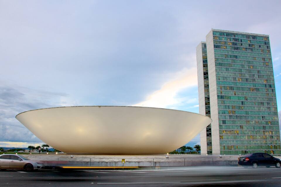 A modern building with a unique bowl-shaped structure in front.