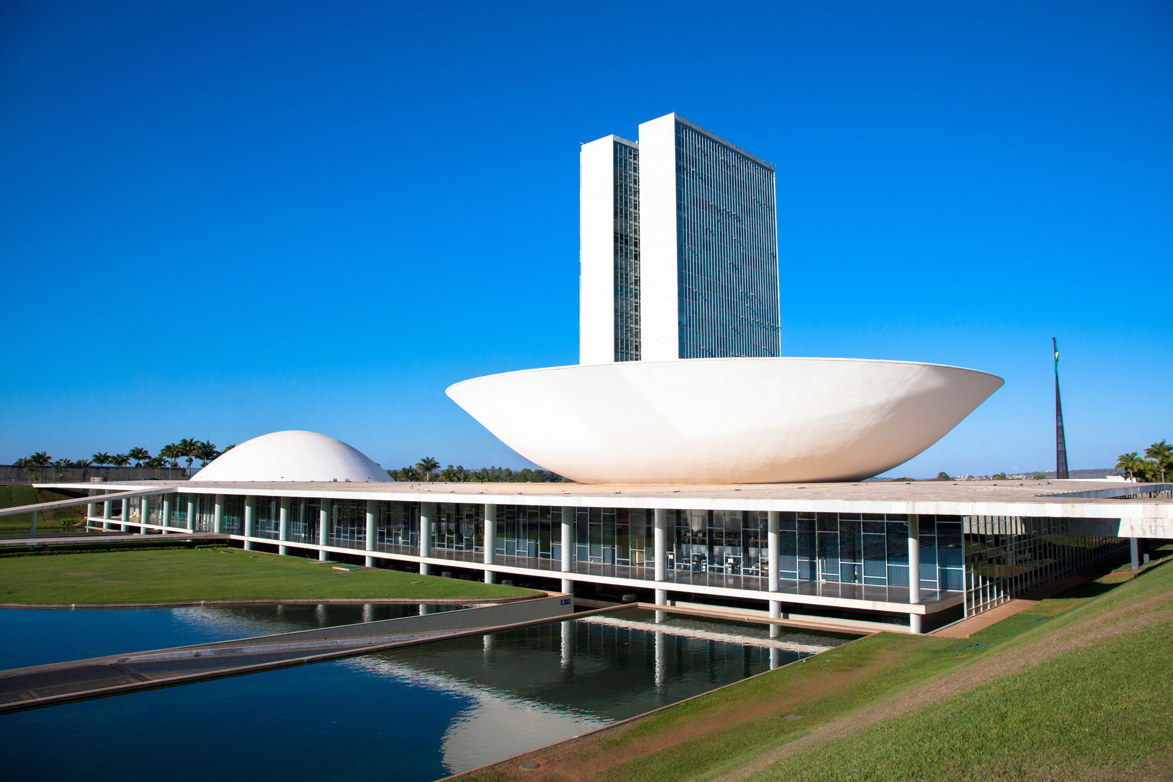 Un edificio moderno con una gran estructura en forma de cuenco blanco y una alta torre rectangular.