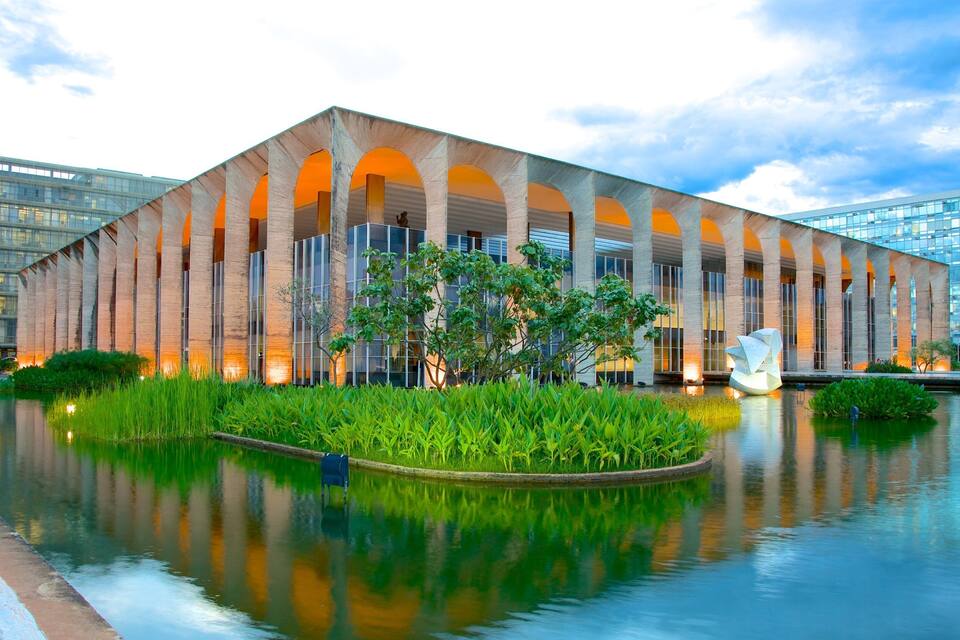 A modern building with arched columns and a reflective water feature in front.