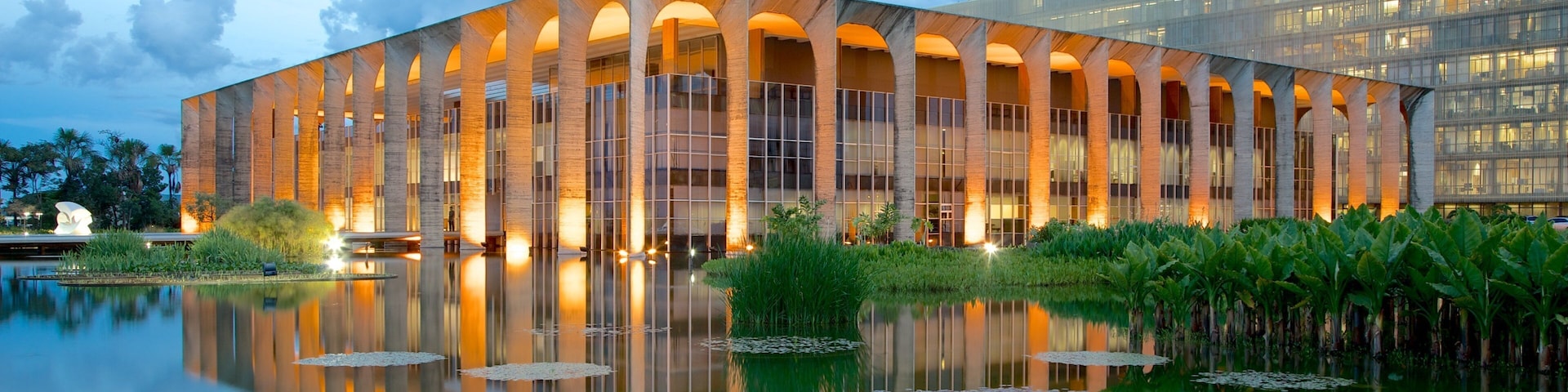 A modern building with a reflective water feature in front.