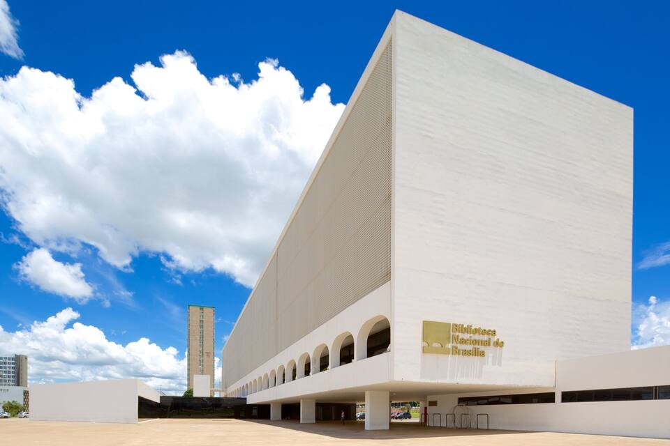 Un edifici modern de color blanc amb una entrada ampla i arquejada i una torre alta al fons.