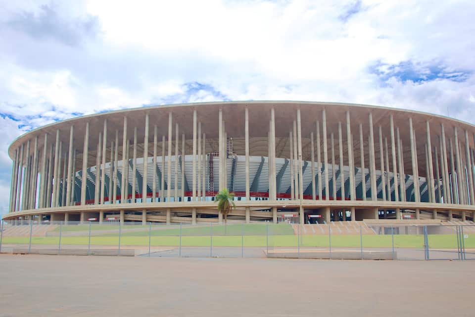 A large, circular stadium with a unique design featuring vertical columns and a tiered seating arrangement.