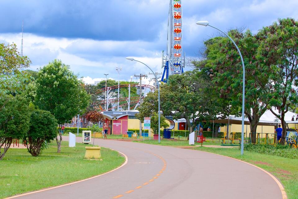 Um parque com uma montanha-russa, árvores, uma estrada sinuosa e um edifício com uma placa.