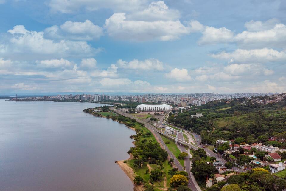 A coastal cityscape with a large stadium, a river, and a mix of urban and green areas.
