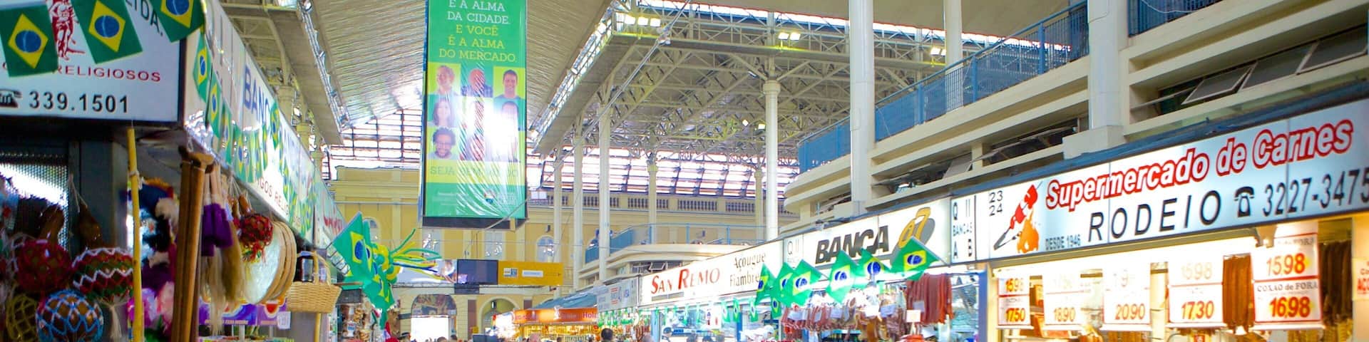 A bustling indoor market with various stalls selling food and goods.