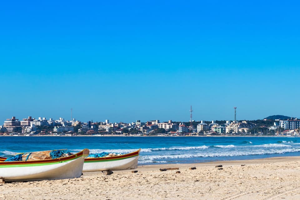 A beach with two boats and a coastal town in the background.