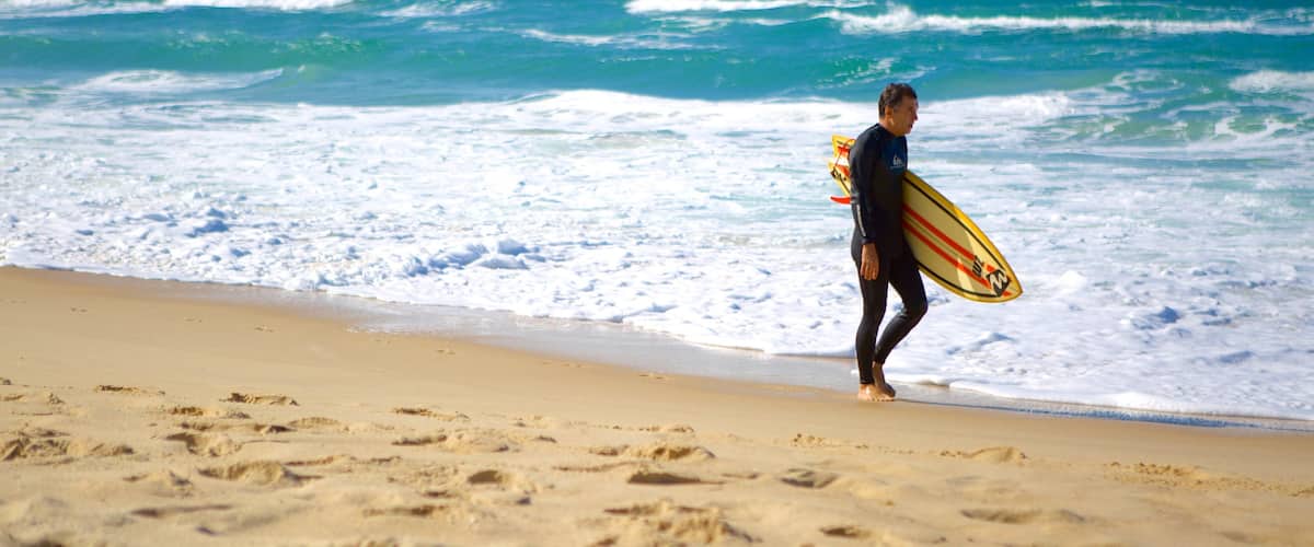 Praia Mole que inclui surfe e uma praia assim como um homem sozinho