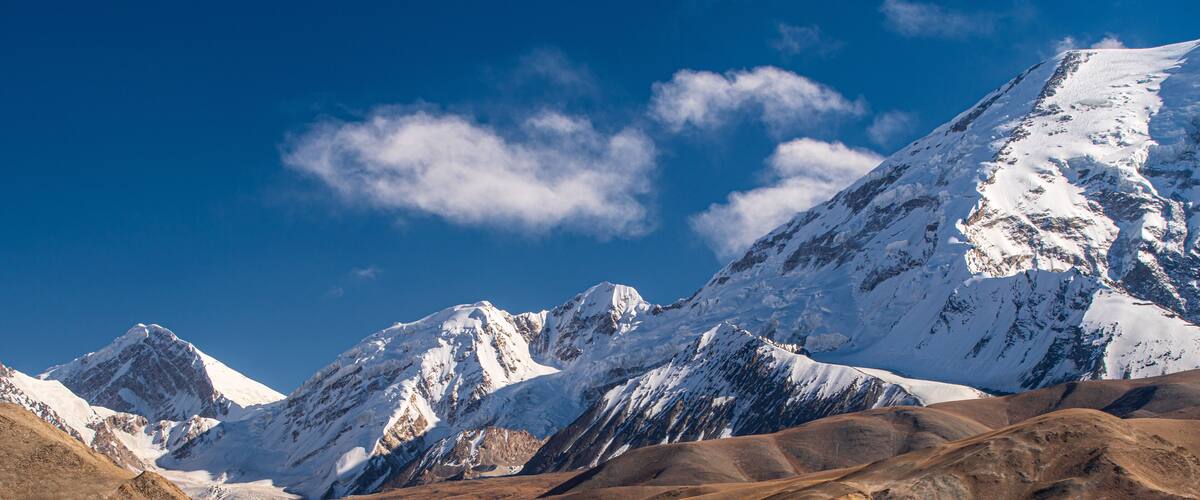 Snow-capped mountains, a desert landscape, and a turquoise lake.
