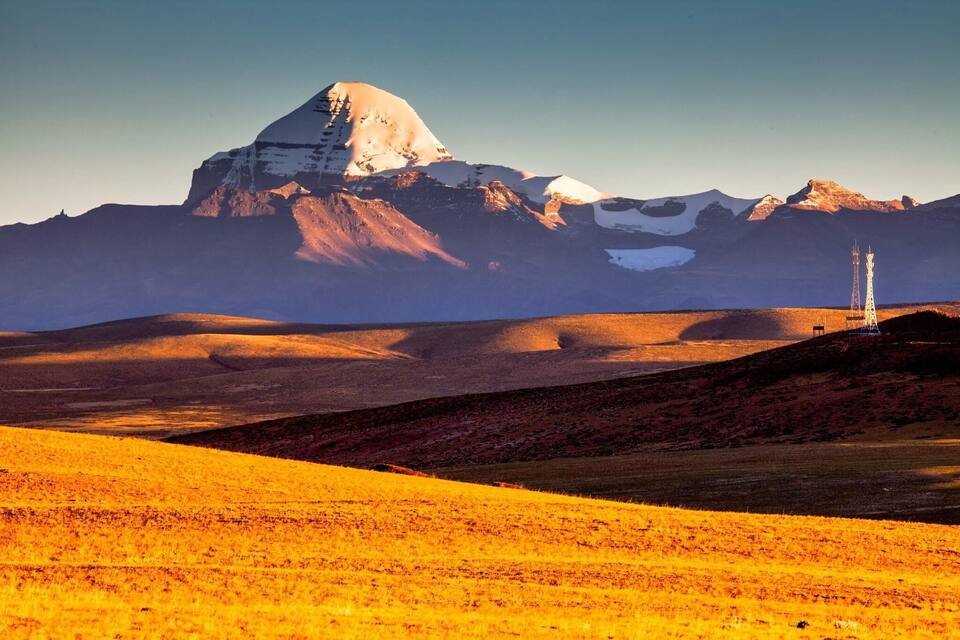 A mountain landscape with a prominent peak, rolling hills, and two communication towers.