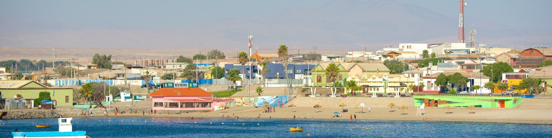 Un pueblo costero con una playa, barcos y edificios coloridos.
