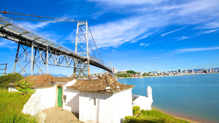 A coastal city with a prominent bridge, a white building with a green door, and a clear blue sky.