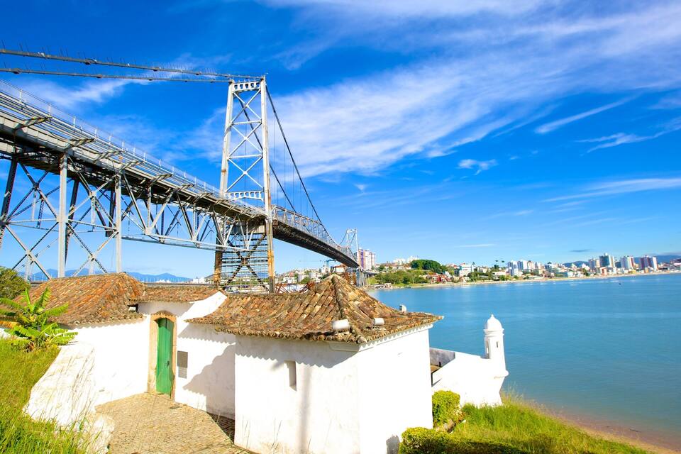 A coastal city with a prominent bridge, a white building with a green door, and a clear blue sky.