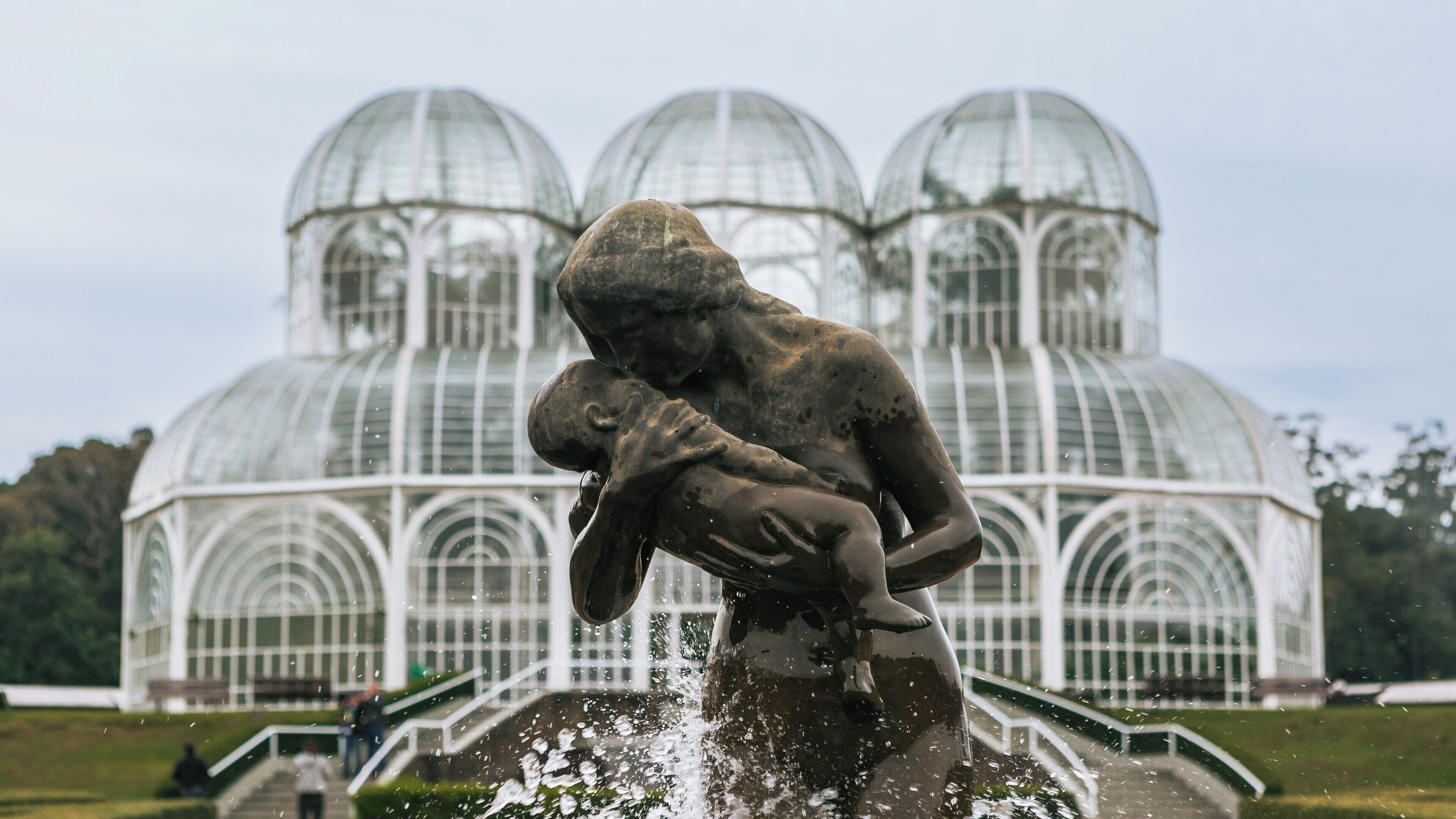 Botanical Garden in Curitiba showcases beautiful glass structures and a mother and child statue amidst serene landscaping