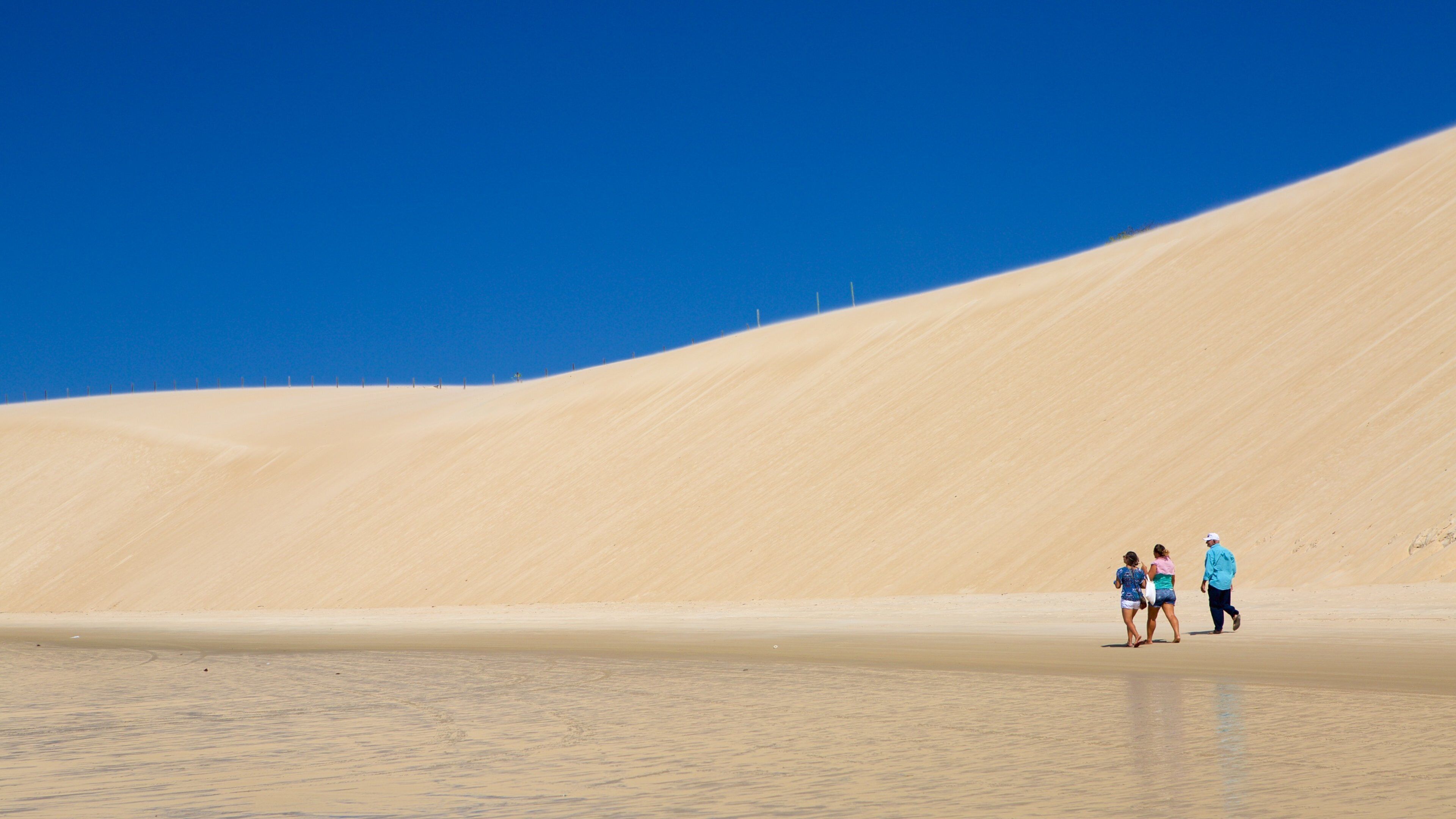 Genipabu strand som inkluderer sandstrand og kyst i tillegg til en liten gruppe med mennesker