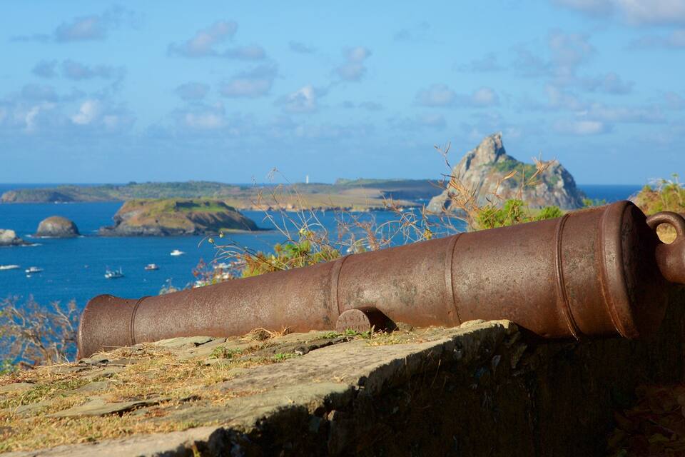 A rusted cannon on a rocky outcrop overlooking the sea.