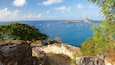 A coastal landscape with a clear view of the sea, rocky terrain, and a small building.