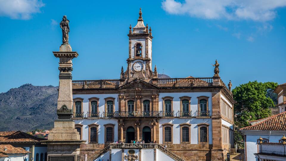 Un bâtiment historique doté d’une tour horlogée, d’une statue et d’un escalier menant à l’entrée.