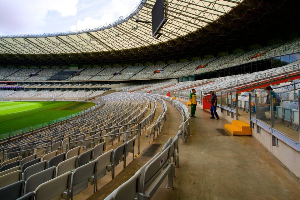 A large, empty stadium with tiered seating and a green field.