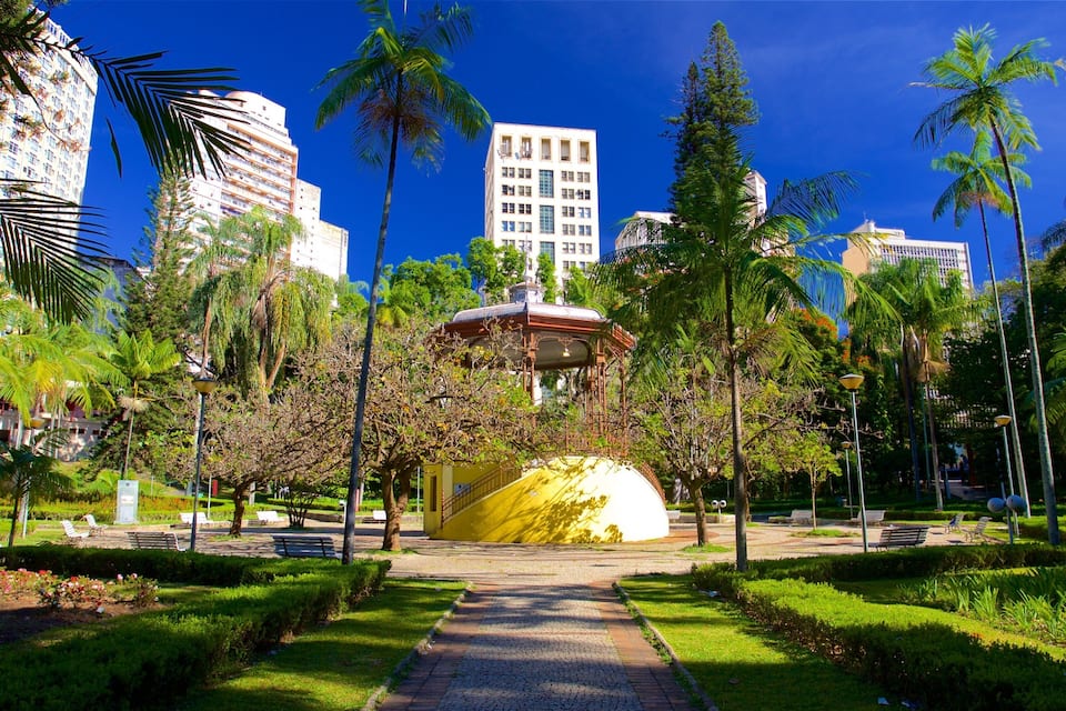 A park with a yellow dome, palm trees, and modern buildings in the background.