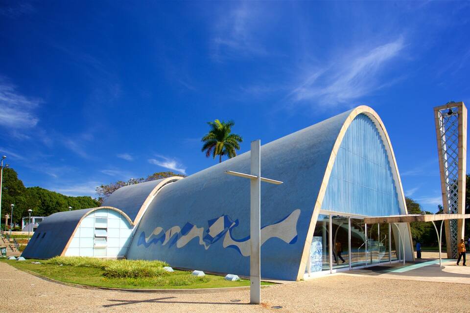 A modern architectural structure with blue and white curved walls, a tall tower, and a palm tree in the background.