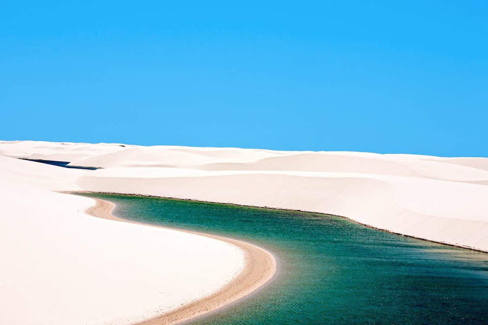 A desert landscape with sand dunes and a clear blue sky.