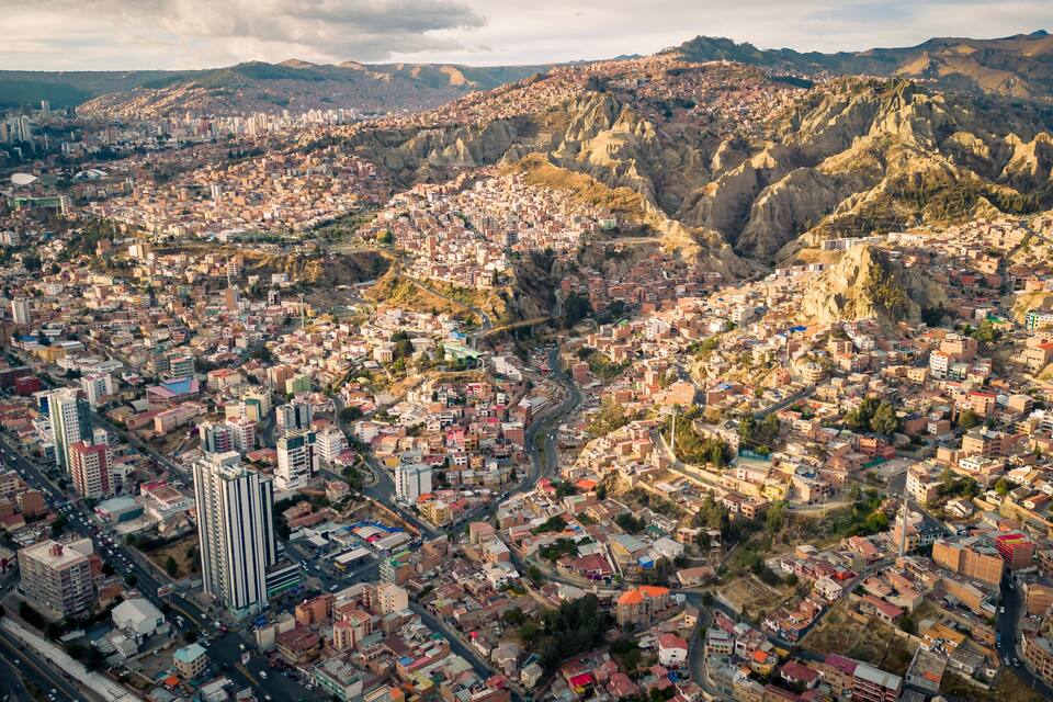 A cityscape with a mix of modern and traditional architecture, surrounded by mountainous terrain.