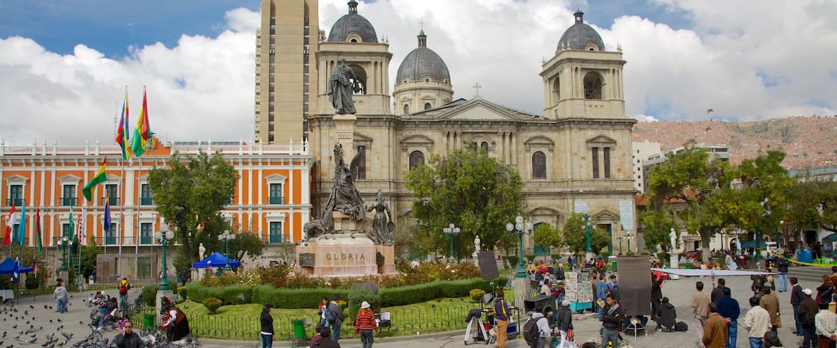 Una plaza con un gran edificio de arquitectura abovedada, una estatua y una fuente.