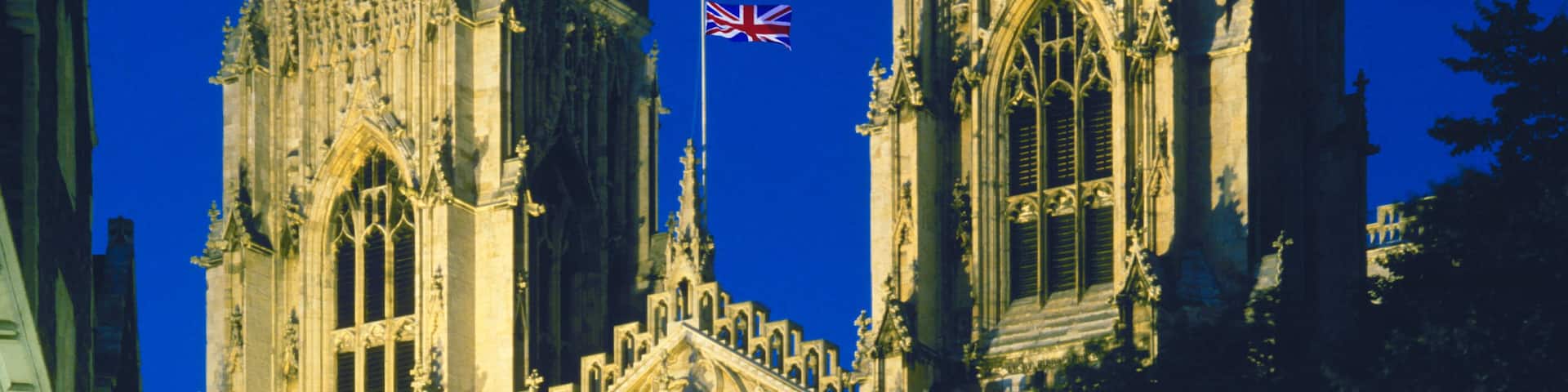 A Gothic cathedral with intricate architecture and a flag.