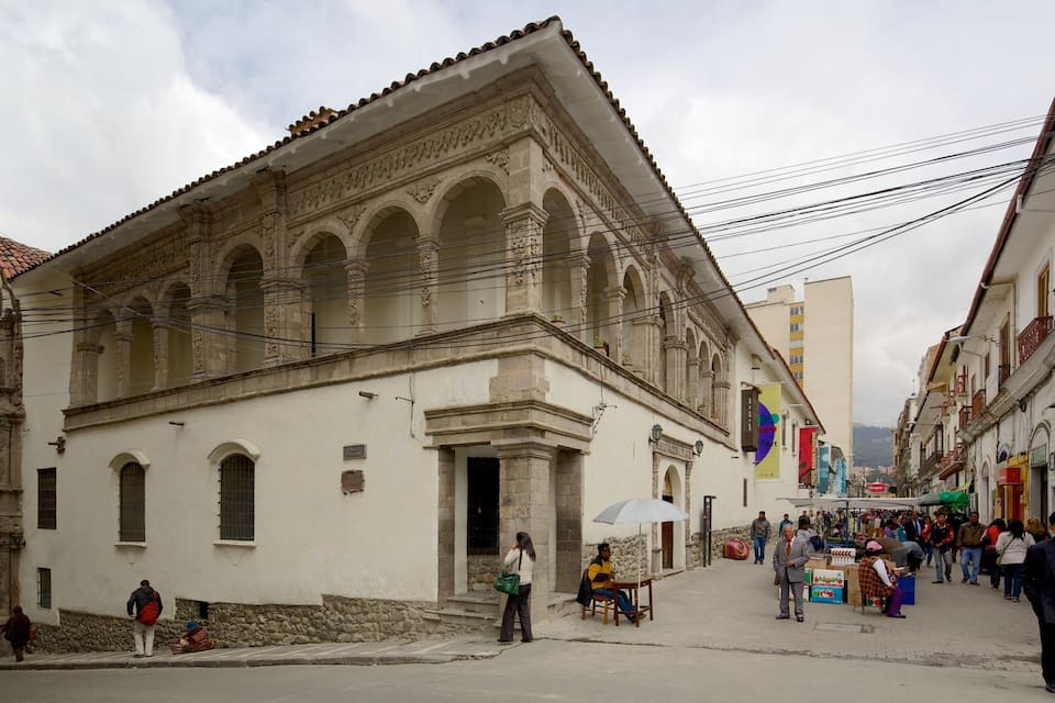 A historic building with ornate architecture, a cobblestone street, and pedestrians.