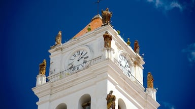 A clock tower with statues and a clear blue sky.