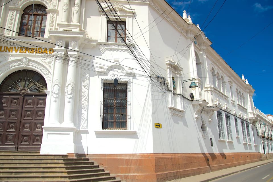 A white building with a large brown door and the word "UNIVERSIDAD" on it.